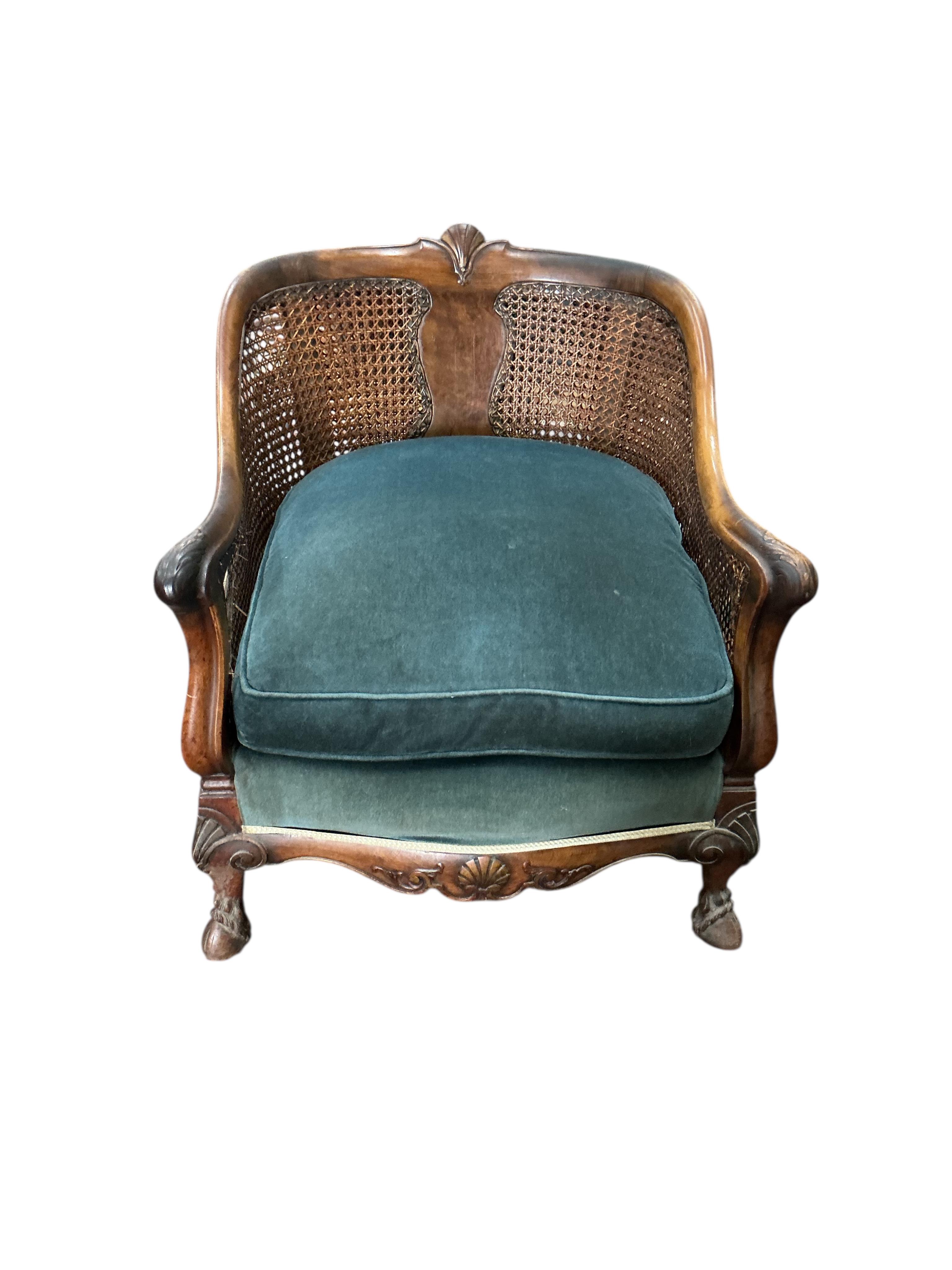 An early 20th century carved walnut and double canework three piece bergère suite, cane in need of repair